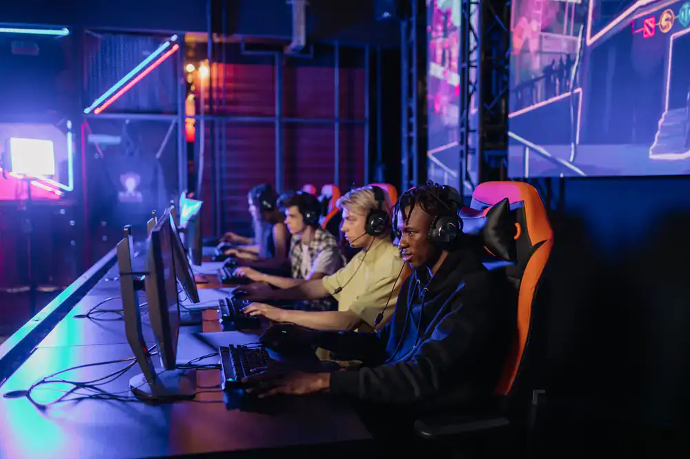 Crowd cheering at a live esports event in a dark gaming lounge